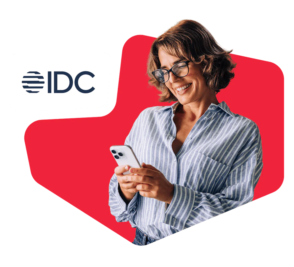 Woman in striped shirt smiling and looking at her smartphone with IDC logo in the background.