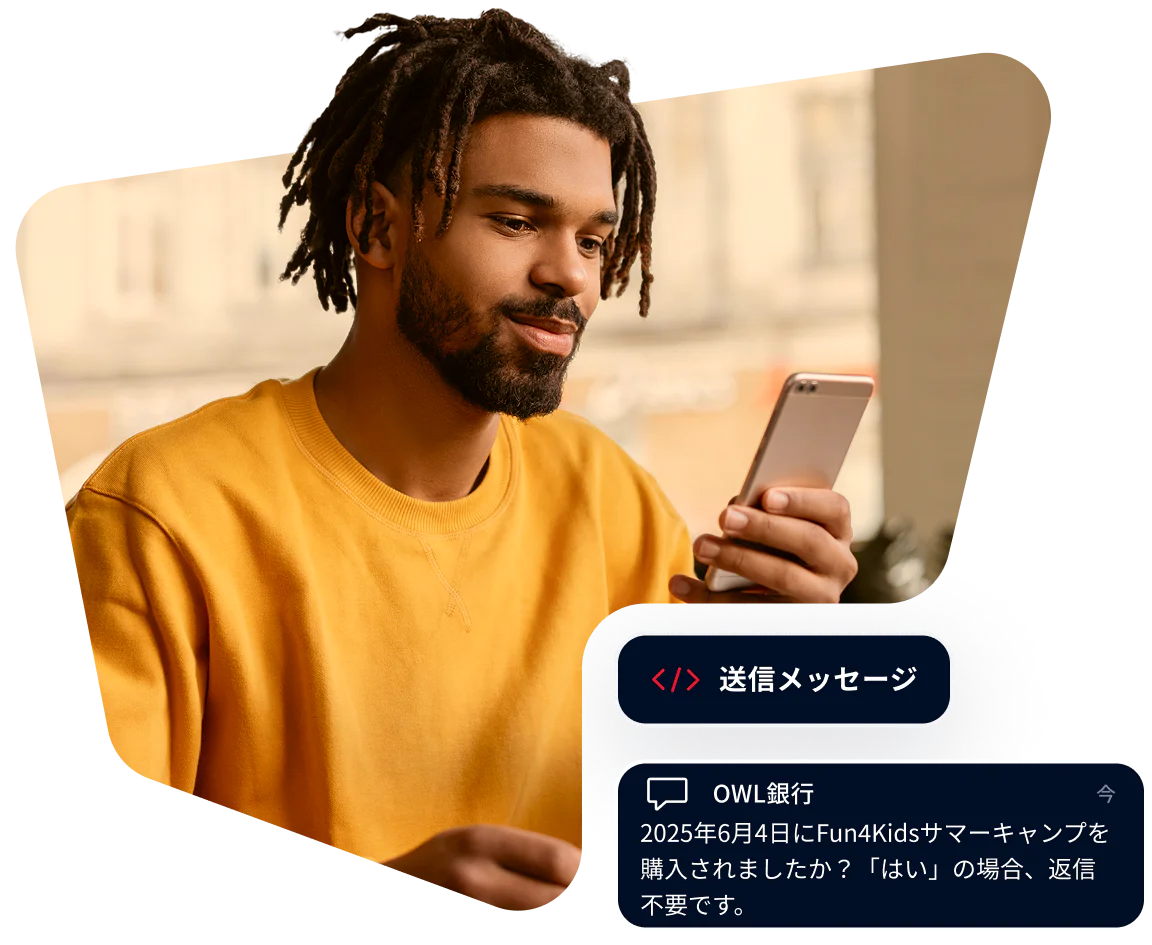 Young Man Receiving a Bank Message on Smartphone Man in yellow shirt looking at phone with a message from Owl Bank about a summer camp purchase.