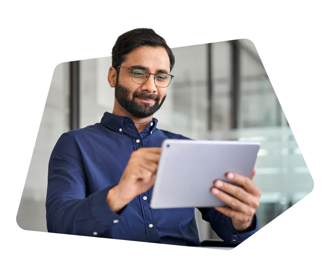 Man with glasses using a tablet while seated in an office environment.