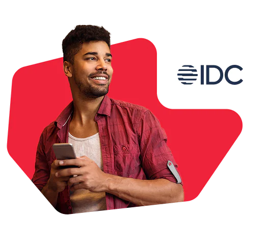 Smiling man in a red shirt holding a smartphone with the IDC logo in the top right corner
