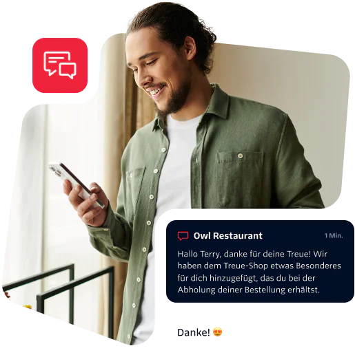 Man in green shirt reading a message on his phone with a smile on his face.