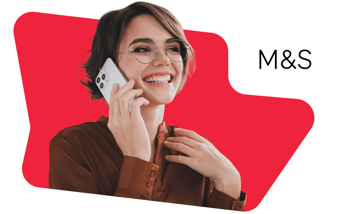 Woman with glasses smiling and talking on the phone, M&S logo in the background