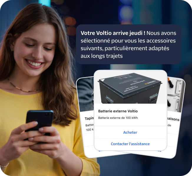 Woman smiling at phone with popup showing road trip essentials like a Voltiq power bank.