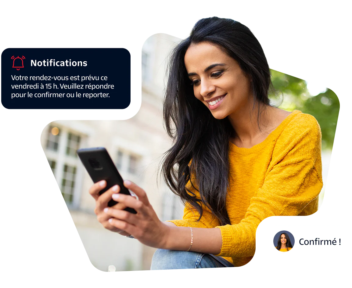 Smiling woman in yellow sweater checks appointment notification on her smartphone.