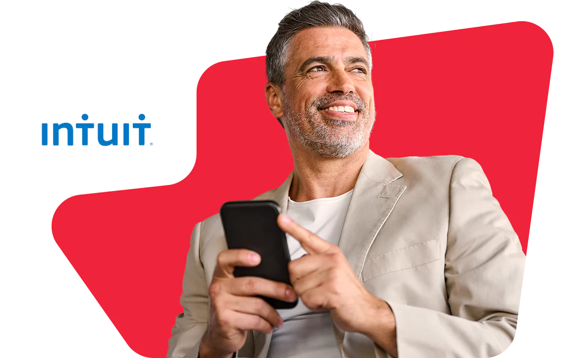 Smiling man holding a smartphone with Intuit logo in the background.