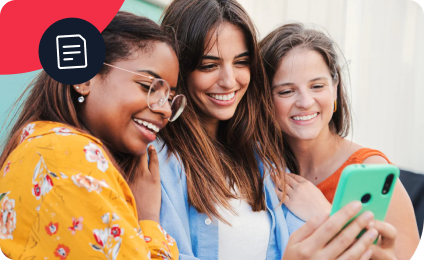 Three smiling women looking at a smartphone, sharing a joyful moment together