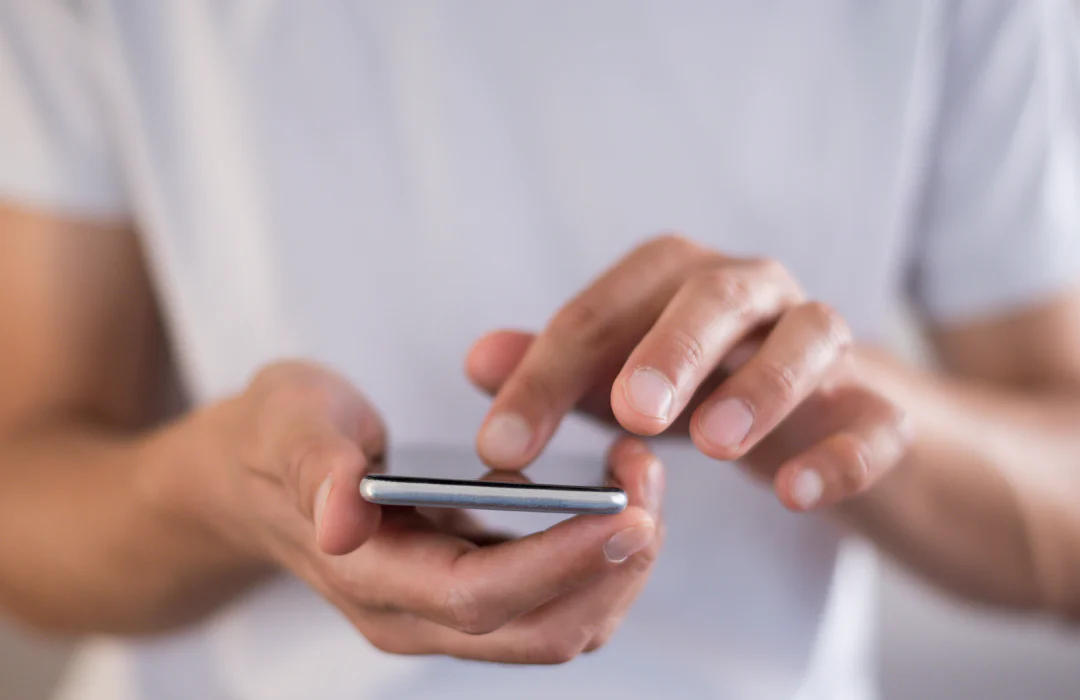 Close-up of a person using a smartphone, with fingers touching the screen.