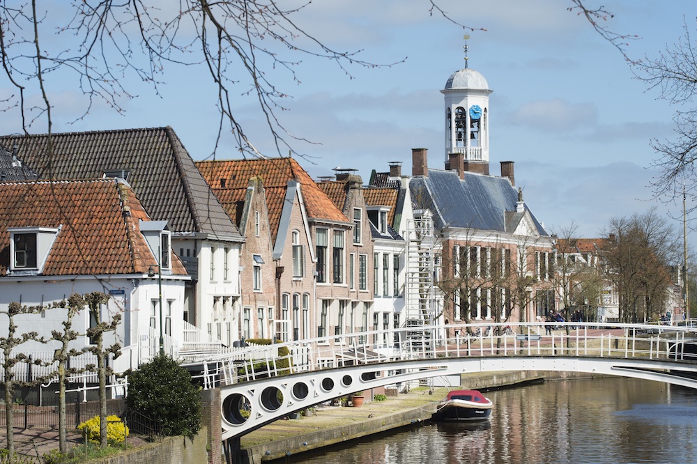 White bridge over a canal with historic European buildings under a blue sky