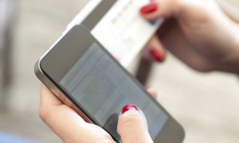 Close-up of hands holding a smartphone and a credit card for an online payment.