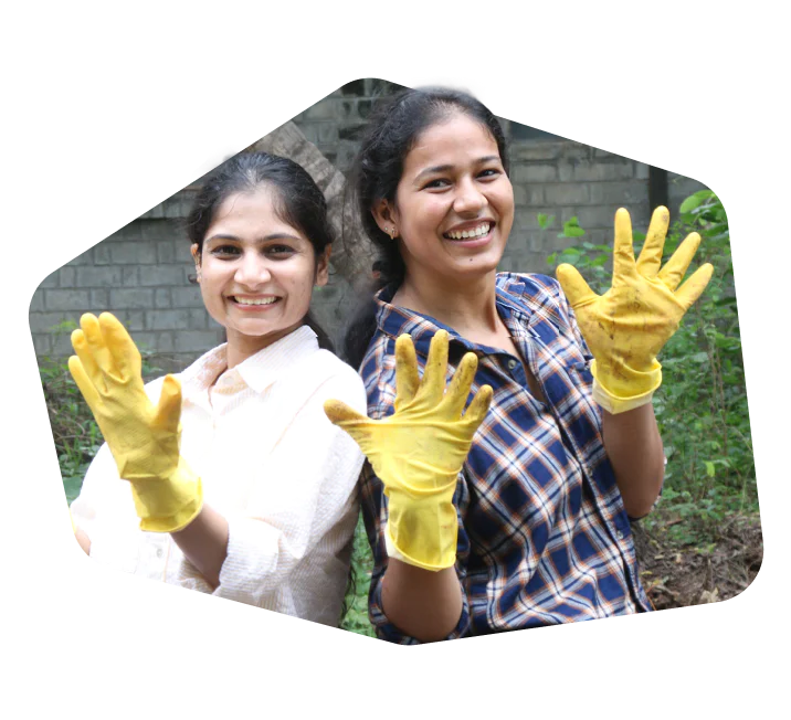 Two women smiling and wearing yellow gloves, standing outdoors.