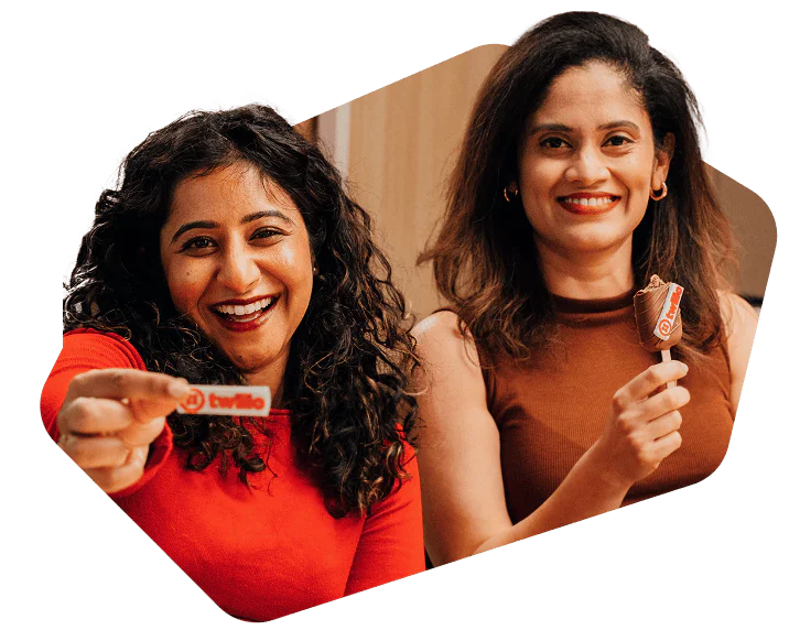 Two women sitting together, one holding a Twilio candy and the other holding an ice cream cone.