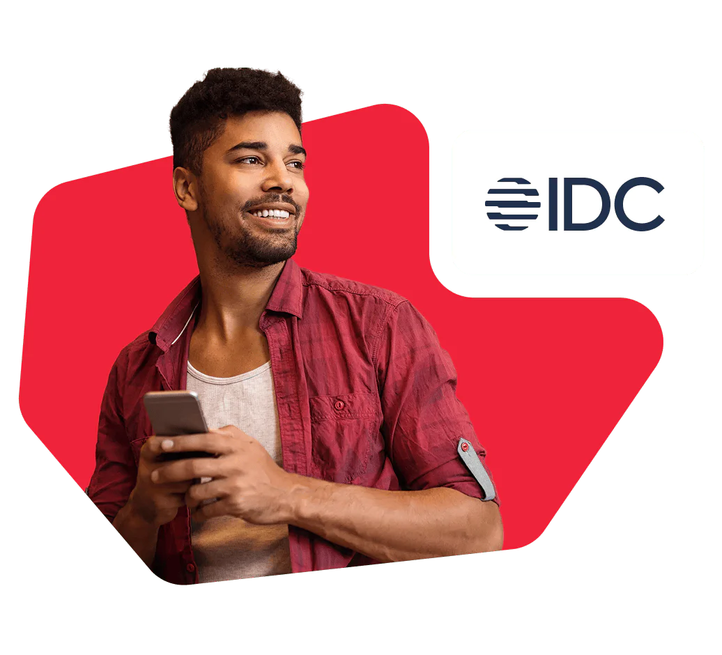 Smiling man in a red shirt holding a smartphone with the IDC logo in the top right corner