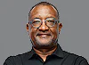 Man with glasses and a black shirt smiling against a grey background Man with glasses and a black shirt smiling against a grey background