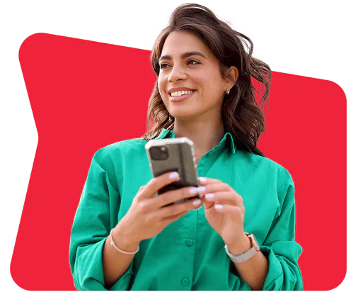 Woman in a green shirt smiling and holding a smartphone.