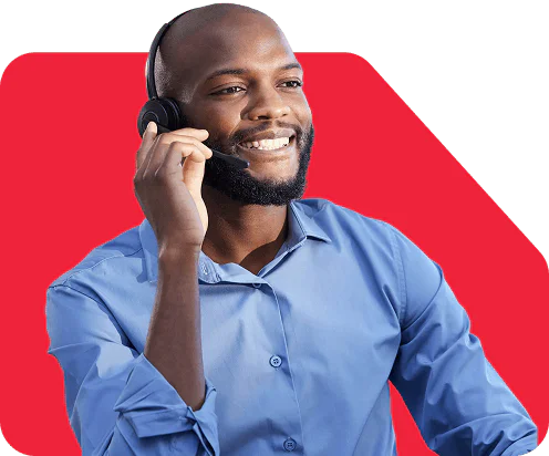 A smiling man wearing a headset and blue shirt, speaking on a call.