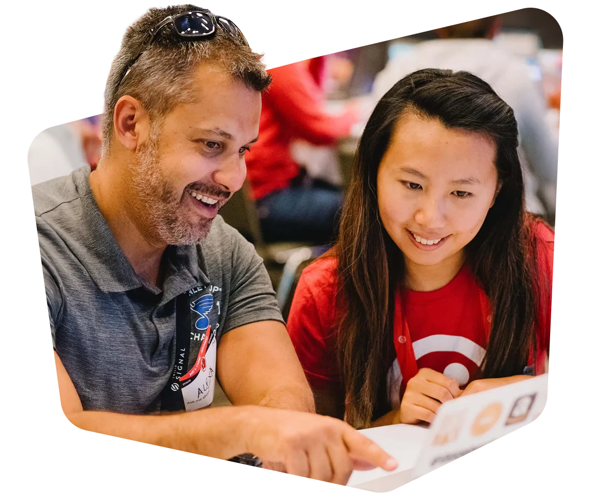 Two people sitting at a table, smiling and looking at a document.