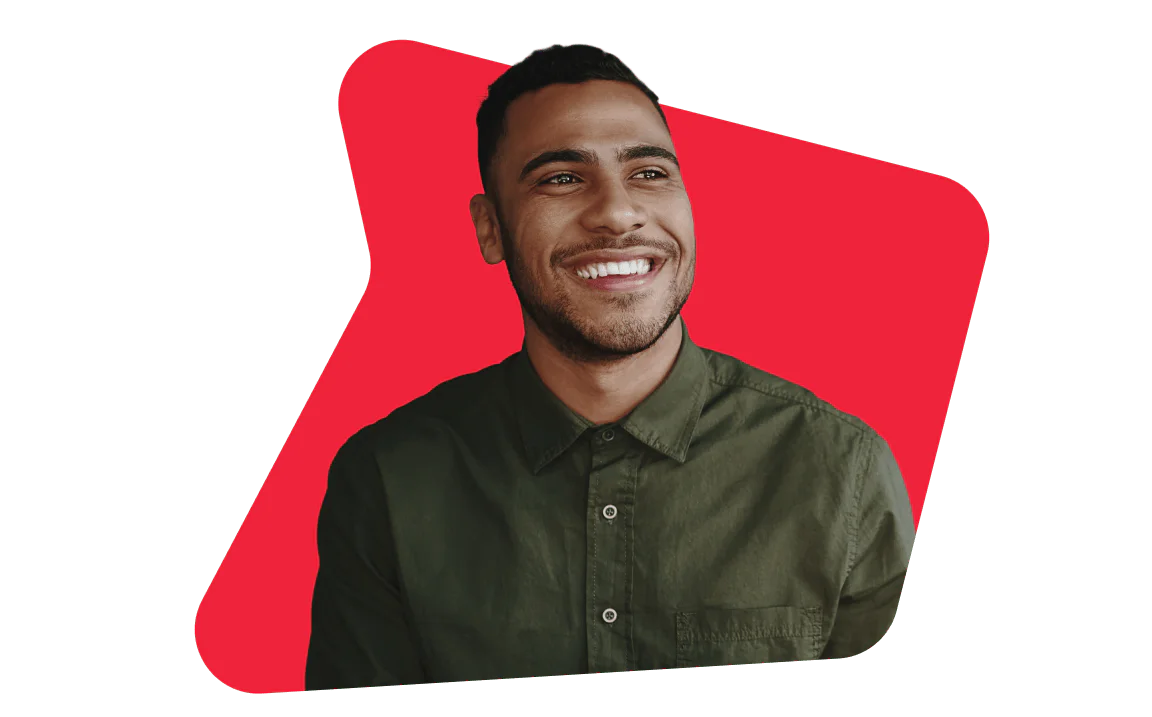 A man with short hair and a beard, wearing a green shirt, smiling against a red background.