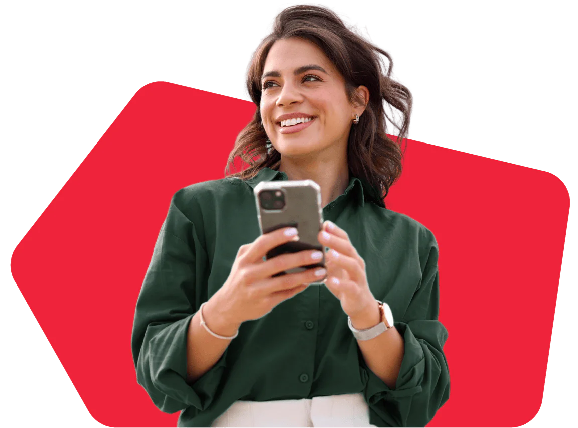 Woman in green shirt holding a smartphone, smiling, with a red geometric shape in the background