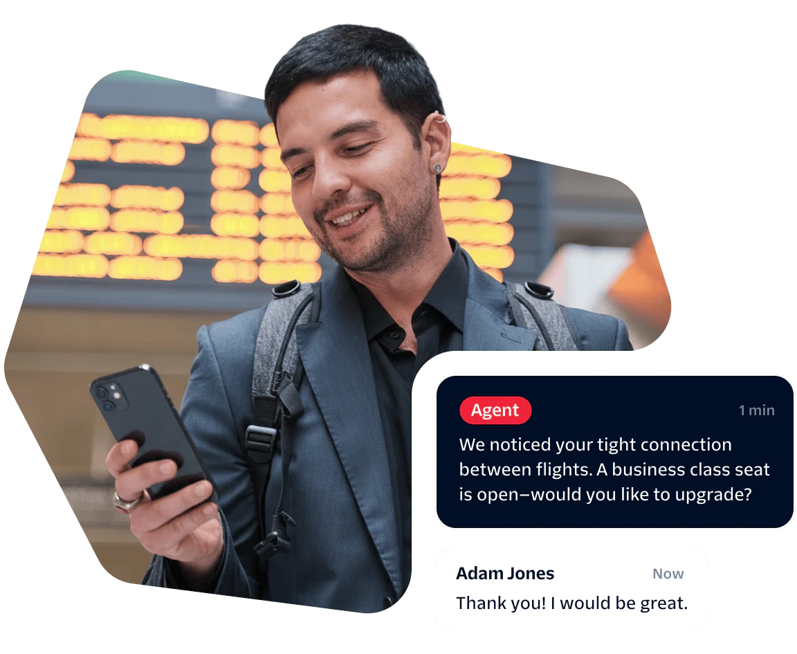 Traveler Receives Upgrade Offer via Mobile App Man checks phone at airport, receives message about upgrading to business class, smiles.