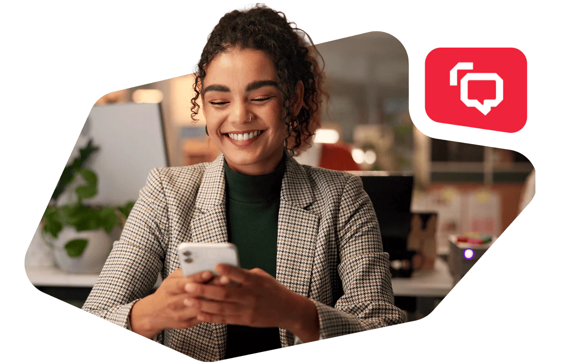 Woman Smiling While Using Smartphone at Work Businesswoman in a plaid blazer looking at her phone and smiling in an office setting.