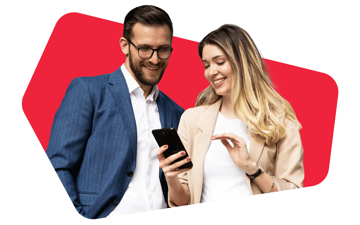Man in blue suit and woman in beige blazer looking at a smartphone and smiling.