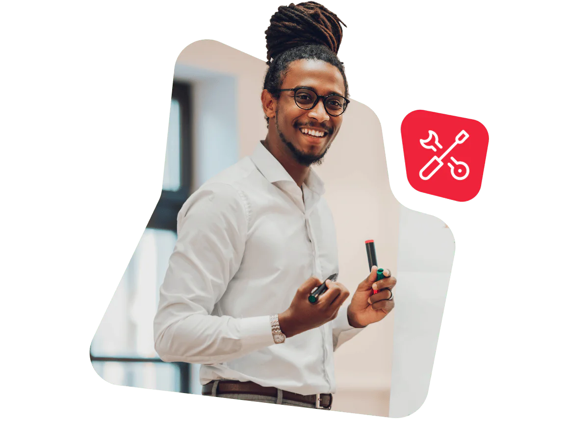 Smiling man with glasses holding markers in a presentation setting.