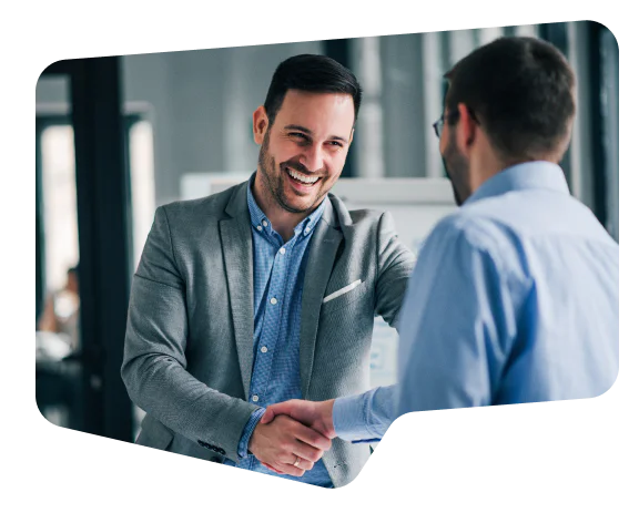 Two men in business attire shaking hands and smiling in a modern office setting.