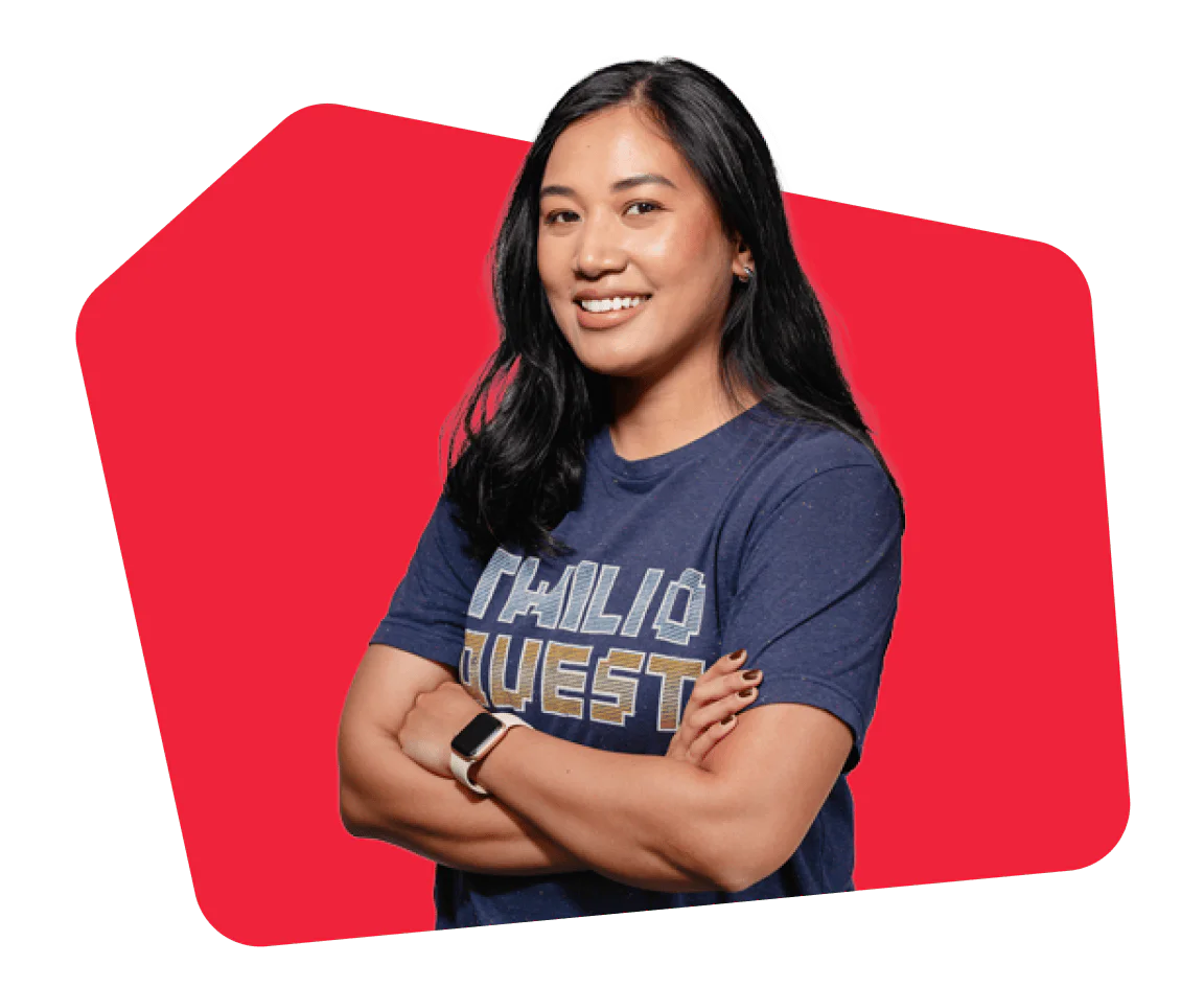 Woman wearing a blue Twilio Quest t-shirt standing with arms crossed.