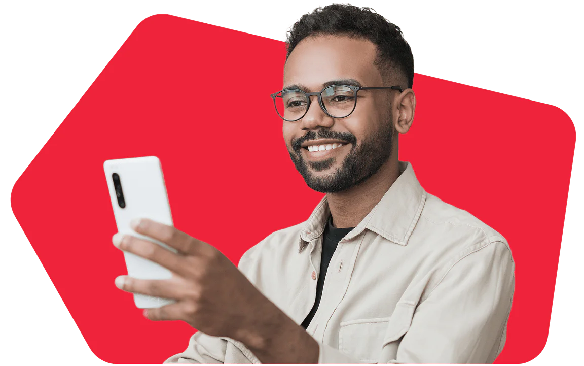 Person Smiling While Using Smartphone A smiling person wearing glasses and a beige shirt is holding and looking at a smartphone.