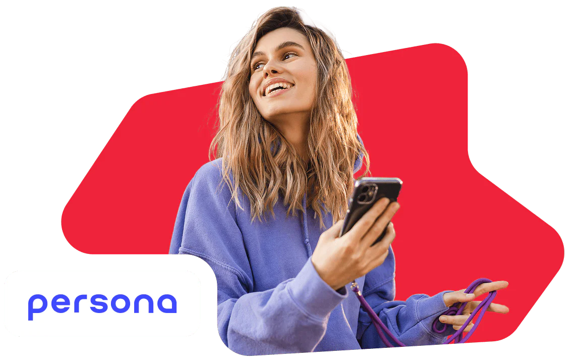 Young Woman Smiling While Holding a Smartphone Smiling woman in a purple hoodie holding a smartphone with a red background.