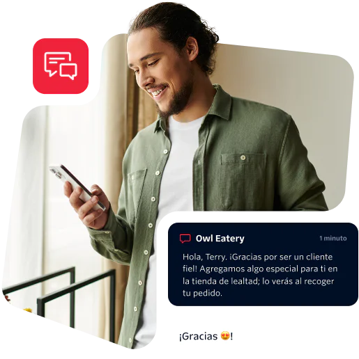 Man in green shirt reading a message on his phone with a smile on his face.