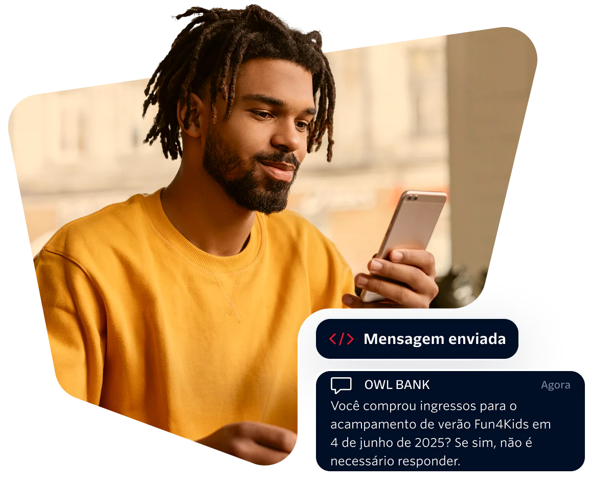Young Man Receiving a Bank Message on Smartphone Man in yellow shirt looking at phone with a message from Owl Bank about a summer camp purchase.